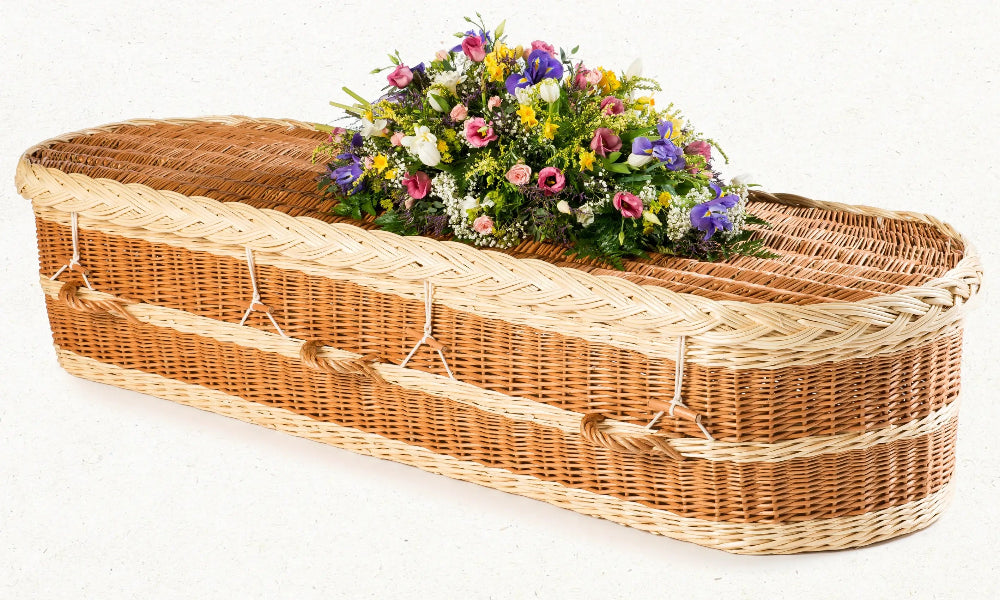 Ecoffins English Willow Light wicker coffin with a floral arrangement on a white background