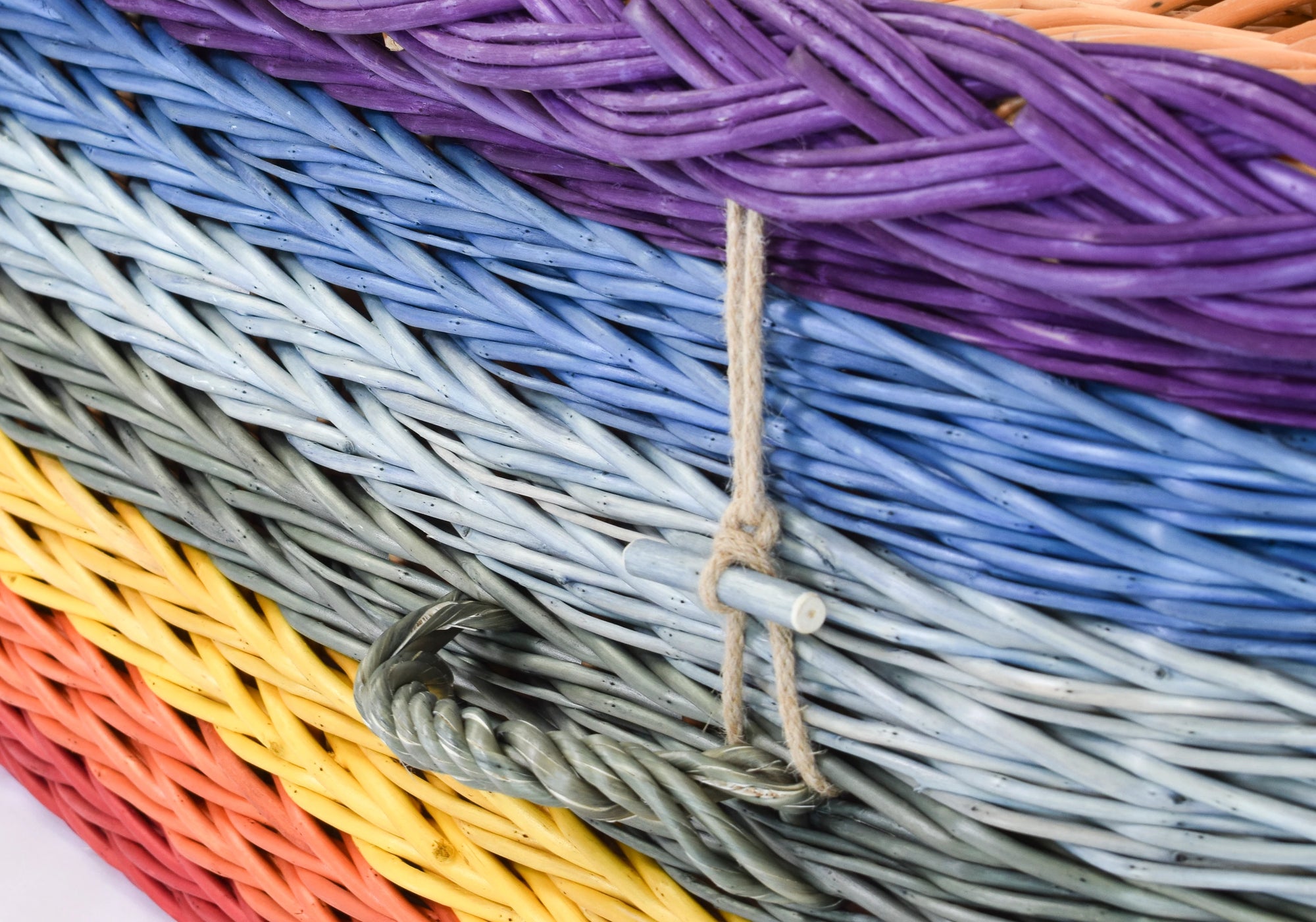 Close up of an English Willow Coffin woven with coloured willow in a rainbow design