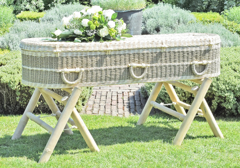 Ecoffins Pandanus Round Coffin on bamboo trestles in a formal garden setting